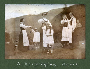  Det er hageselskap på Rophaug i 1913. Tenestejentene dansar ”a Norwegian dance” og har med seg eit par småjenter i kvite kjolar. Tenestejentene var frå lokalsamfunnet, småjentene ser ut til å vera av fint folk, kanskje engelske gjester. 