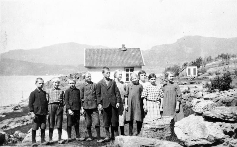  I 1925 fotograferte lærar Oluf Bjelland elevane ved Finnvik skule i Imsland (Vindafjord kommune). Biletet viser også miljøet rundt skulehuset og det vesle uthuset i bakgrunnen. Oluf Bjelland må ha vore ein dyktig amatørfotograf med godt kamera. Dette fotografiet har like god teknisk kvalitet og like god komposisjon som bileta dei profesjonelle fotografane tok når dei stilte barna opp på strame rekkjer. Foto: Oluf Bjelland. 