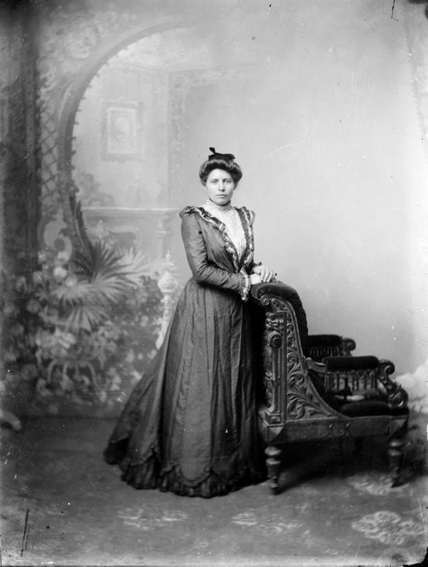 Atelierfotografi av ukjent dame. Stolen i bildet er en av fotoatelierets ofte brukte rekvisitter. Bakgrunnen er den samme som er brukt i DFF-EHT1125 (ovenfor, av skoleklassen). Cirka 1890-1910. Foto: E. H. Torjusen, DFF-EHT0095.