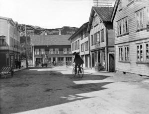 Her er en syklist i Johan Feyers gate på vei mot torvet med mange parkerte hestekjøretøyer. Året er 1914.