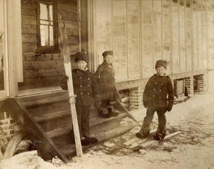  Det er vinter og litt snø, og dei tre eldste borna Edward, Olive og Harold i Archerfamilien er ute. Gutane prøver seg på ski, Olive er enno tilskodar. Bildet er truleg frå 1887. 
